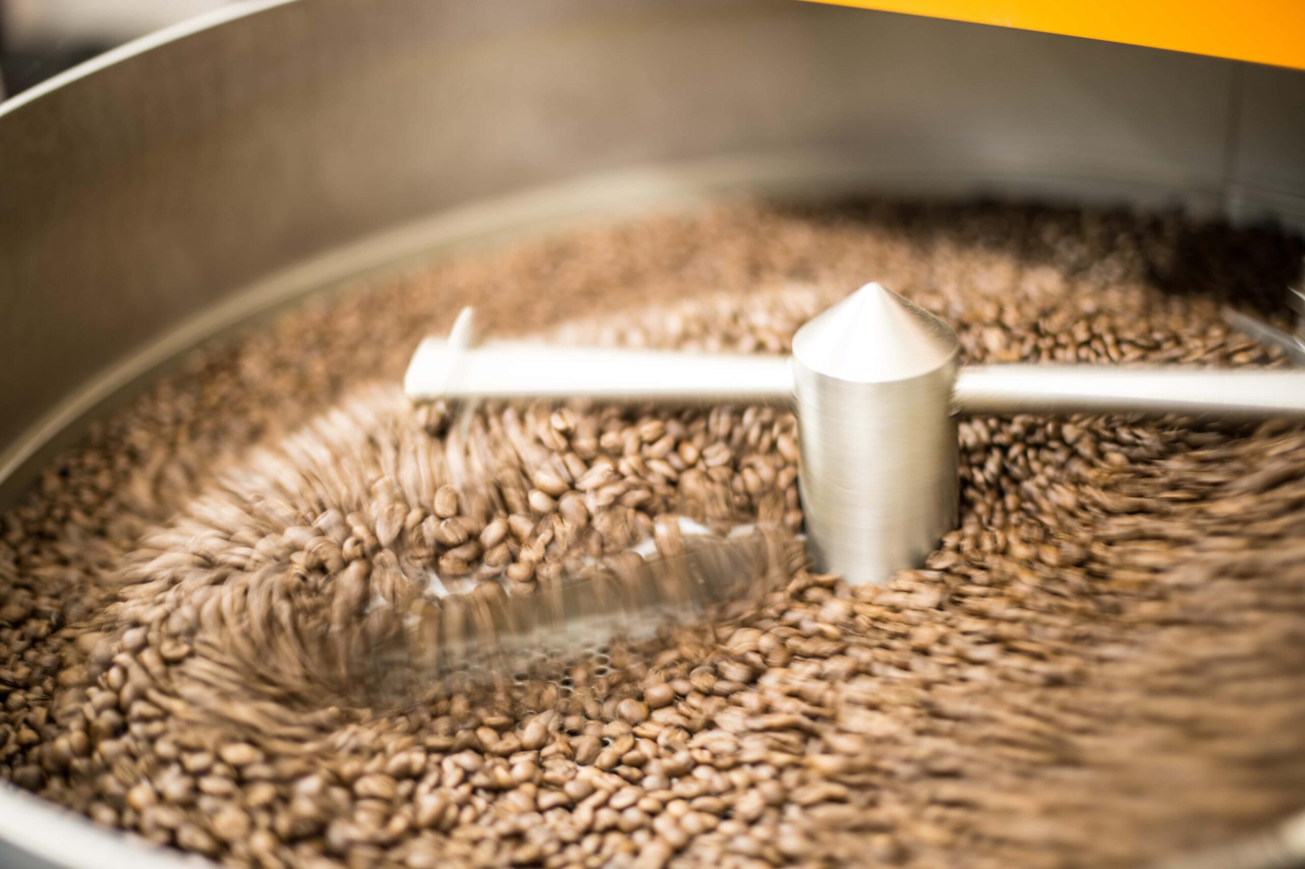 Roasted coffee beans being pushed around a coffee cooling bin