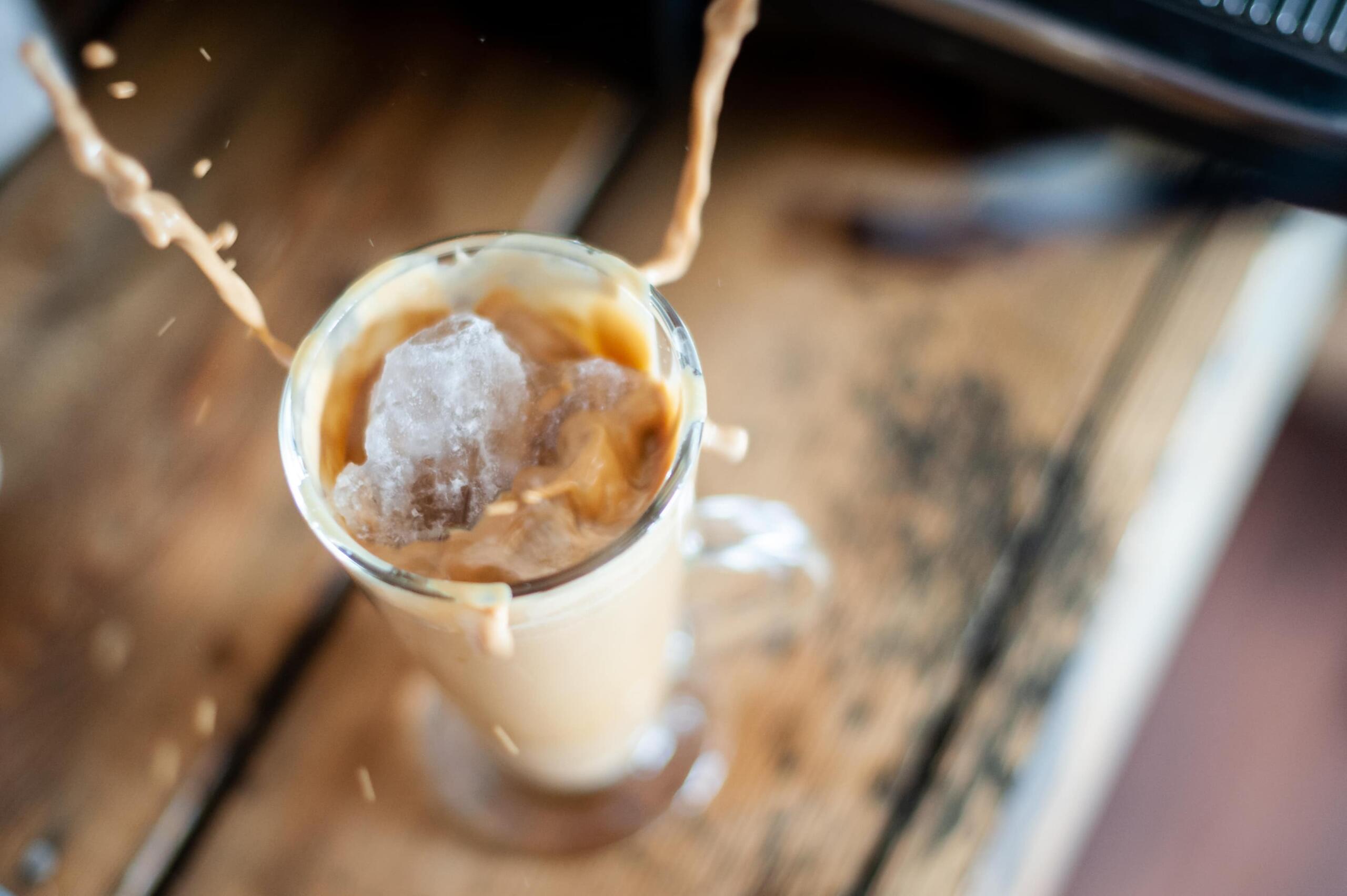 ice cube dropping into iced coffee from above 