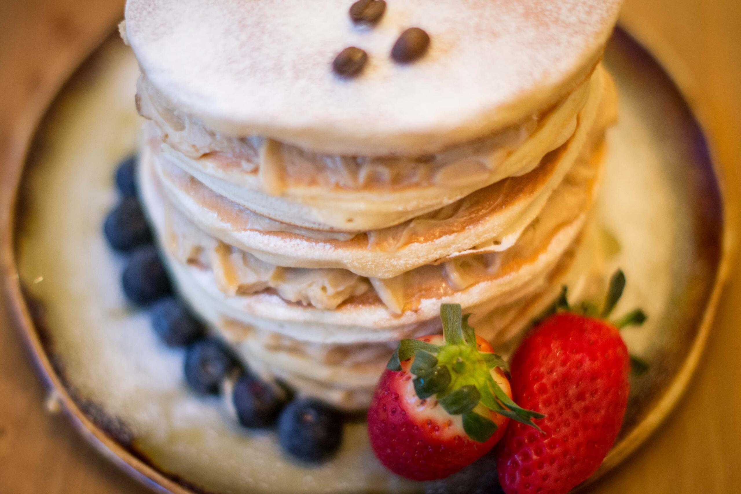 stack of coffee pancakes with coffee whip and fruit