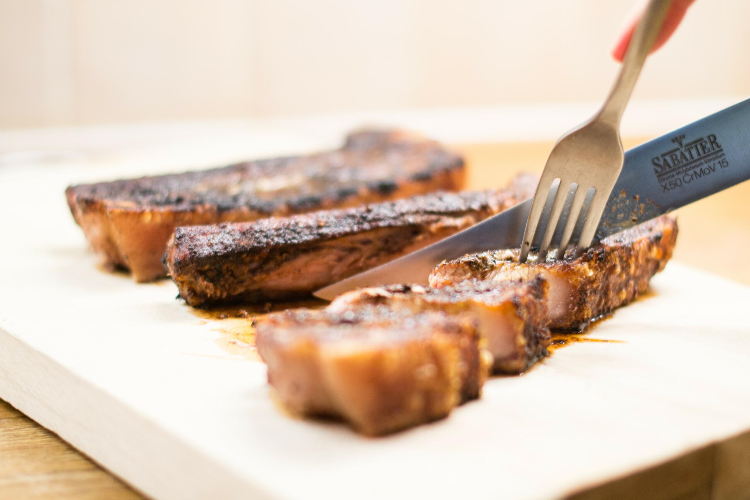 slicing cooked pork belly with a knife and fork