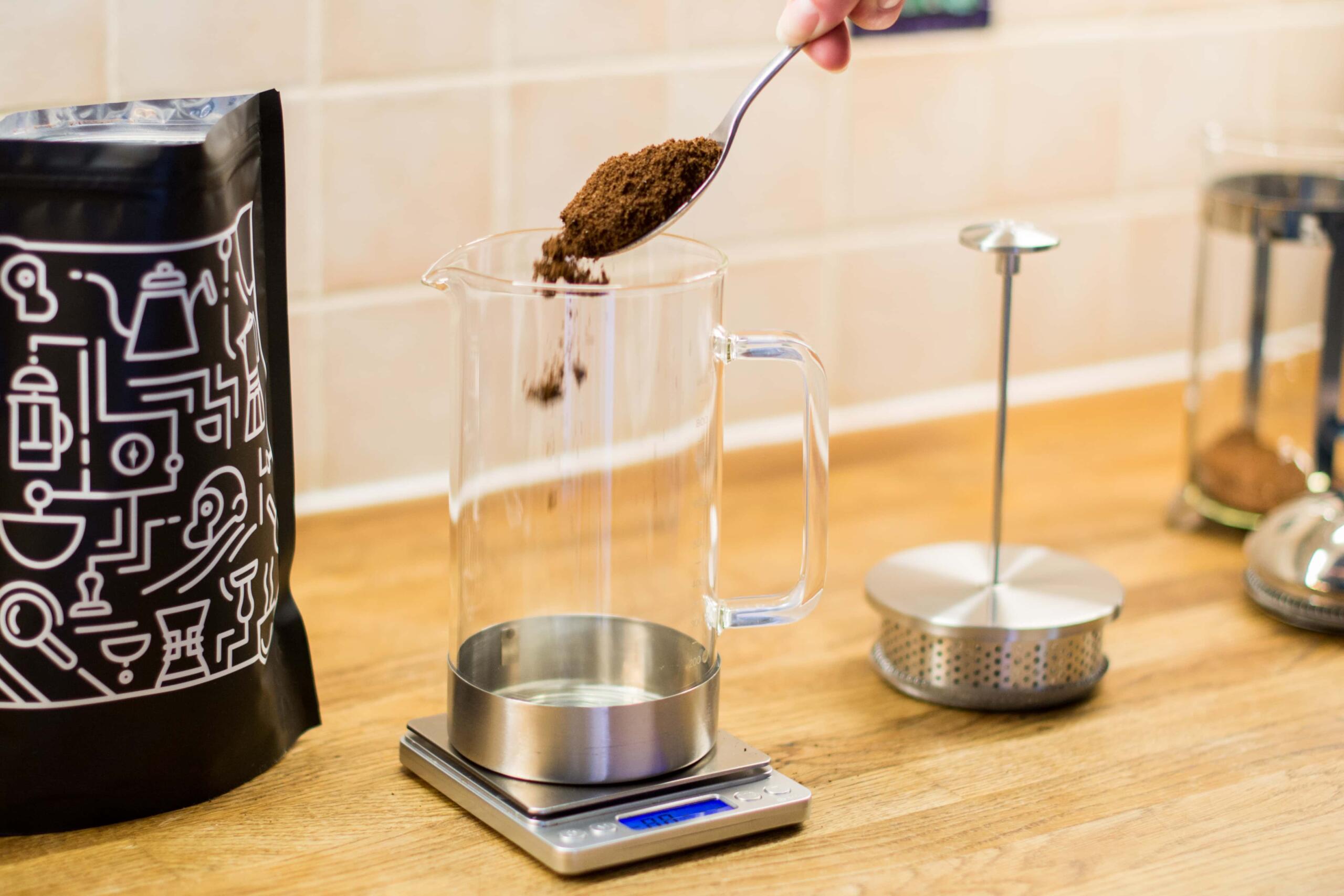 pouring coffee from a spoon into an empty cafetiere