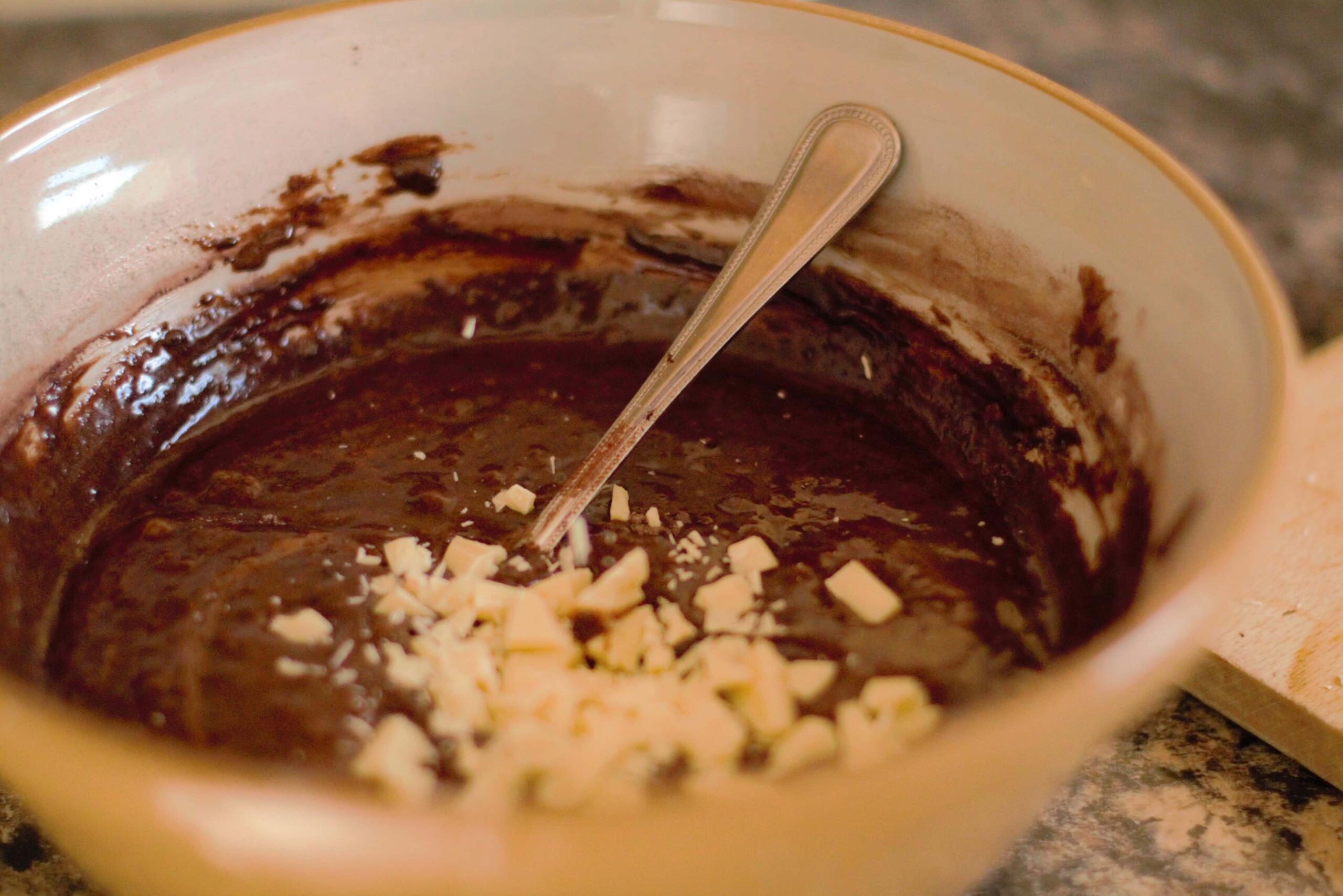 white chocolate chunks in bowl of brownie batter 