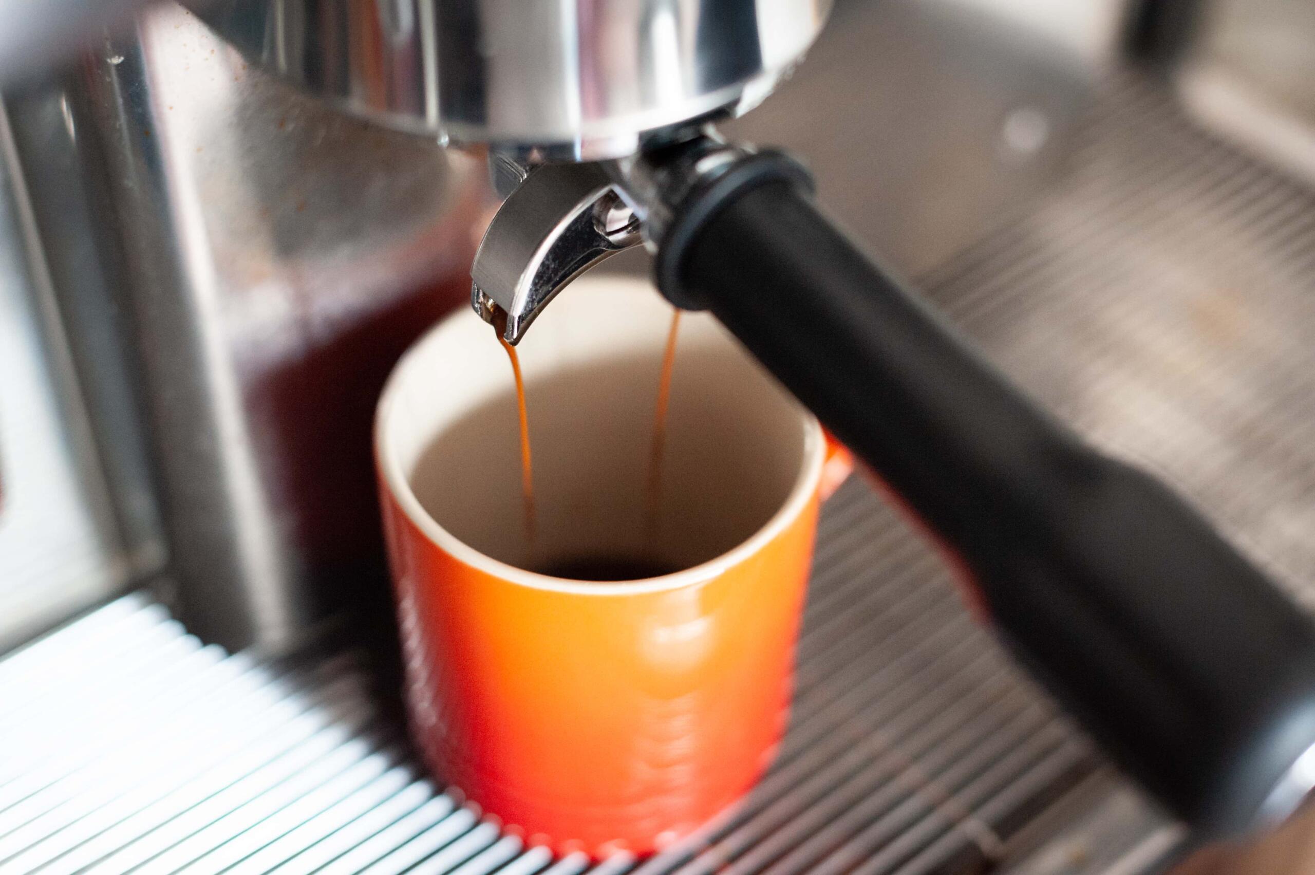 Espresso pouring into orange mug