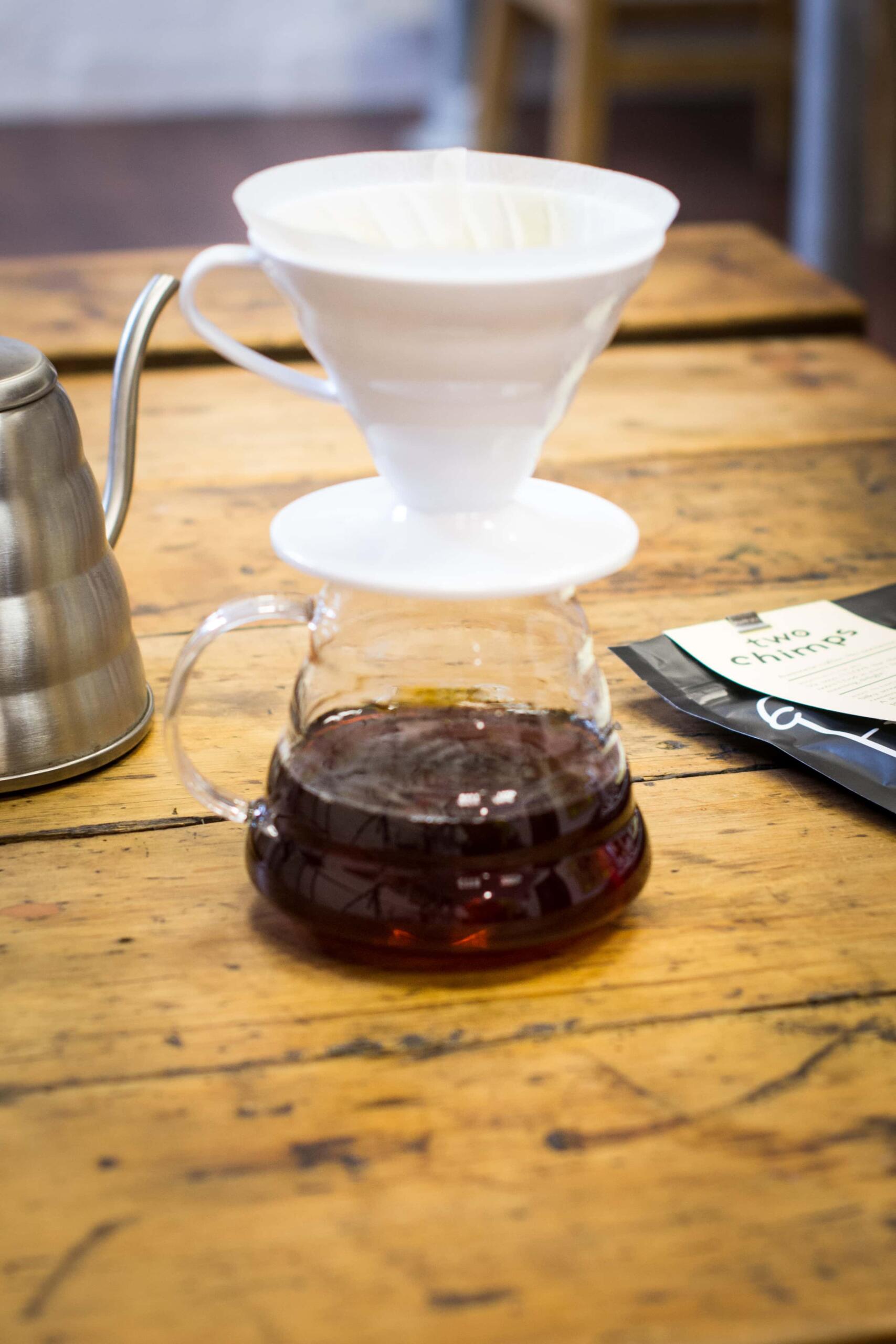 white v60 coffee dripper sitting on a plastic container with brewed coffee in