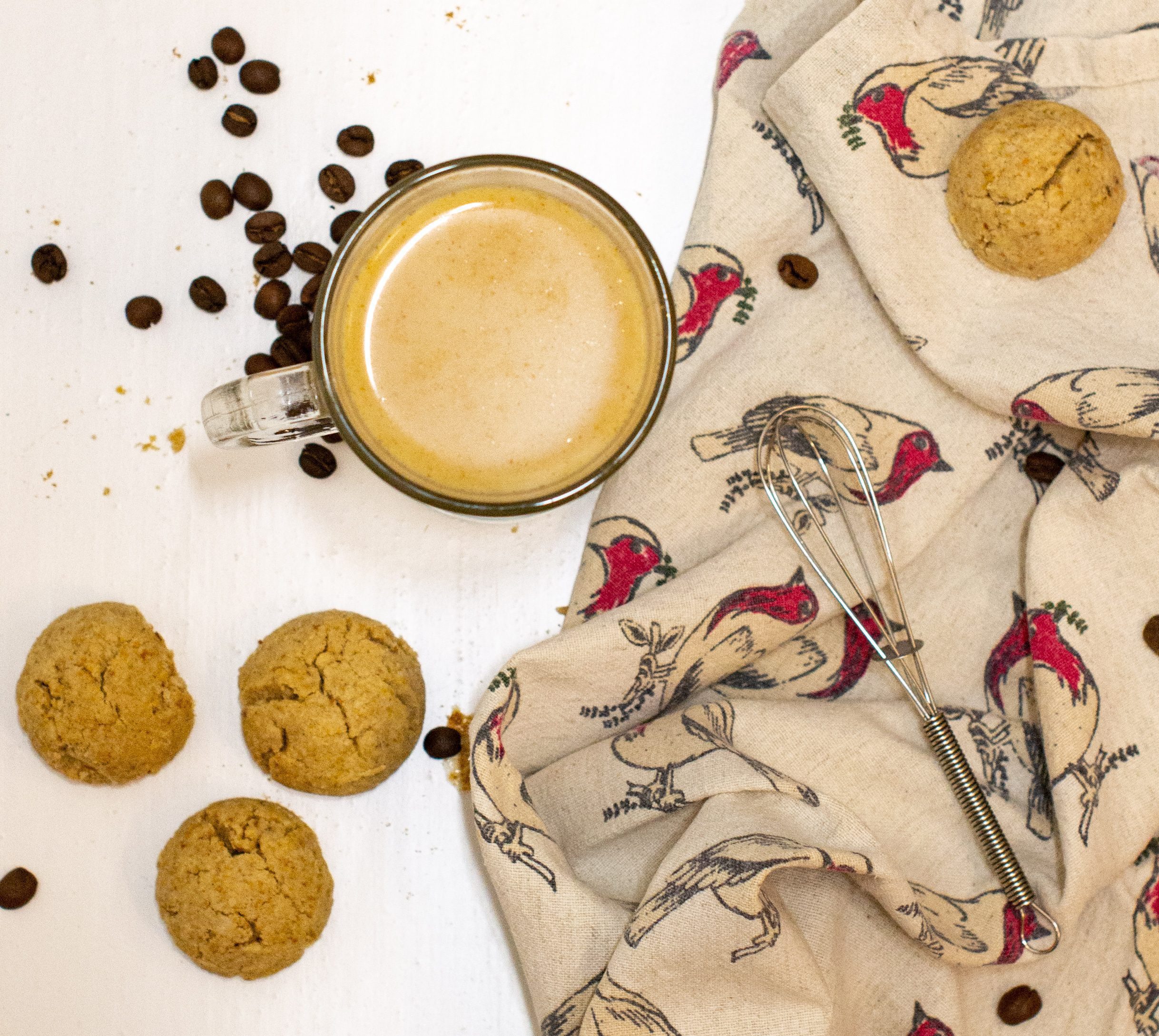 Overhead shot of gingerbread spice latte with cookies and coffee beans and Christmas tea towel