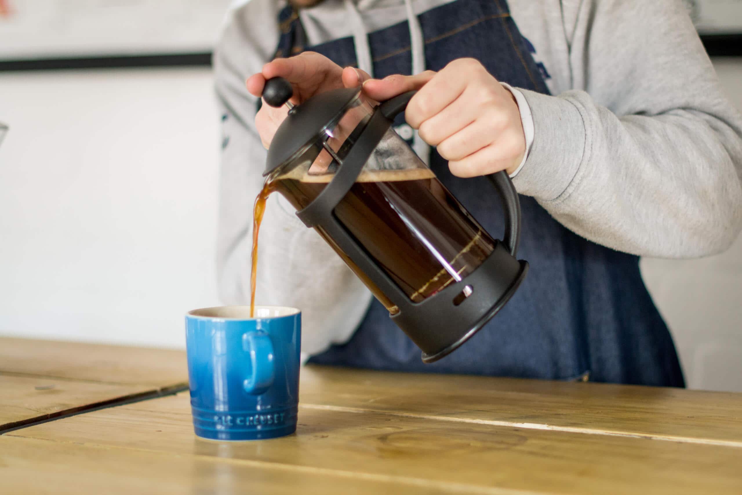 Pouring coffee from a cafetiere into a blue mug