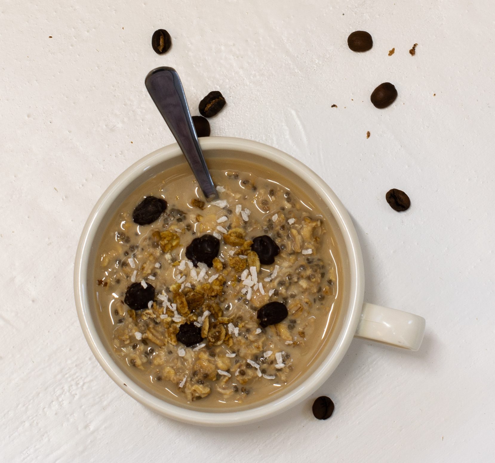 Coffee overnight oats in a white mug with teaspoon