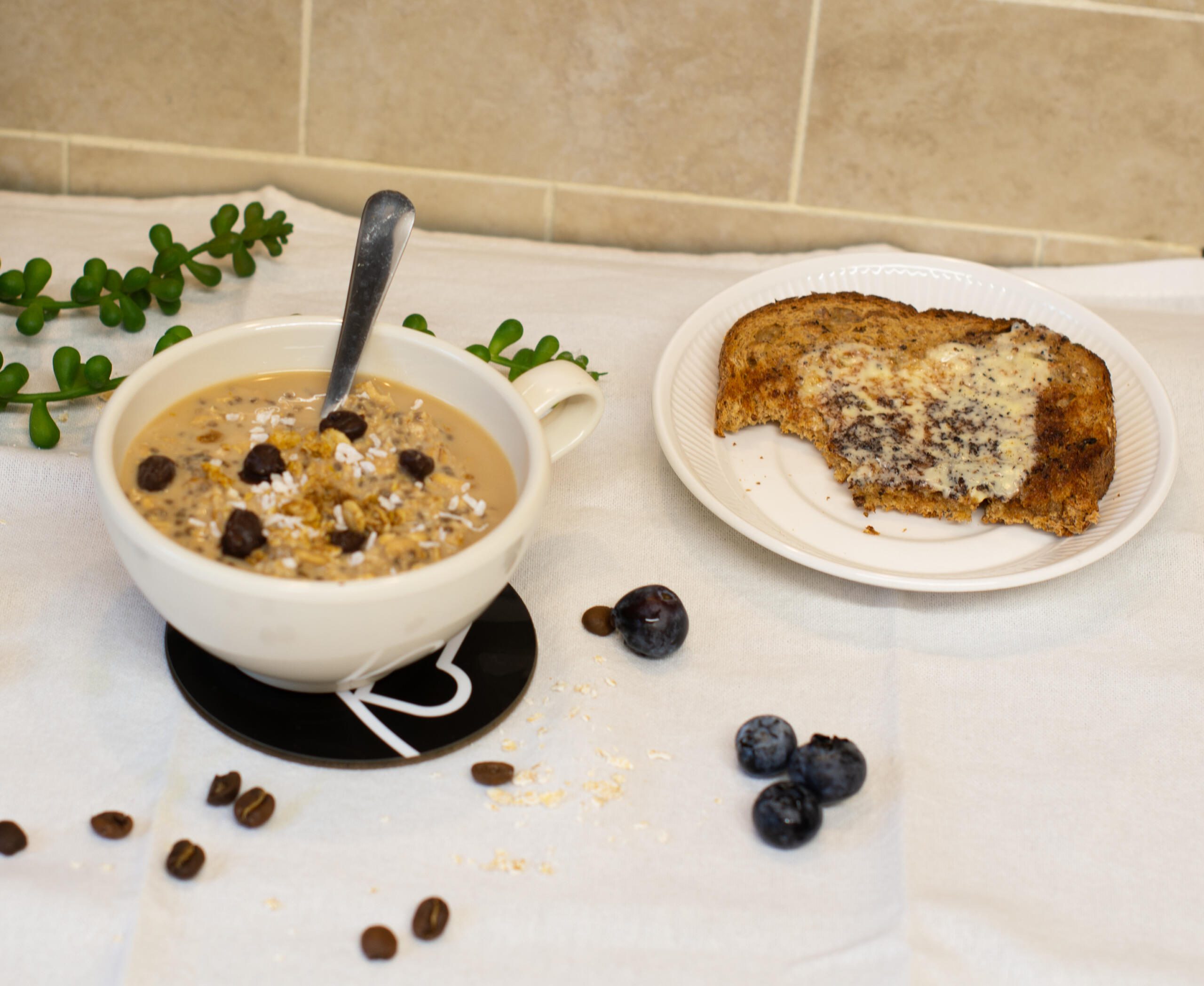 Bowl of coffee porridge beside blueberries and piece of toast and butter 