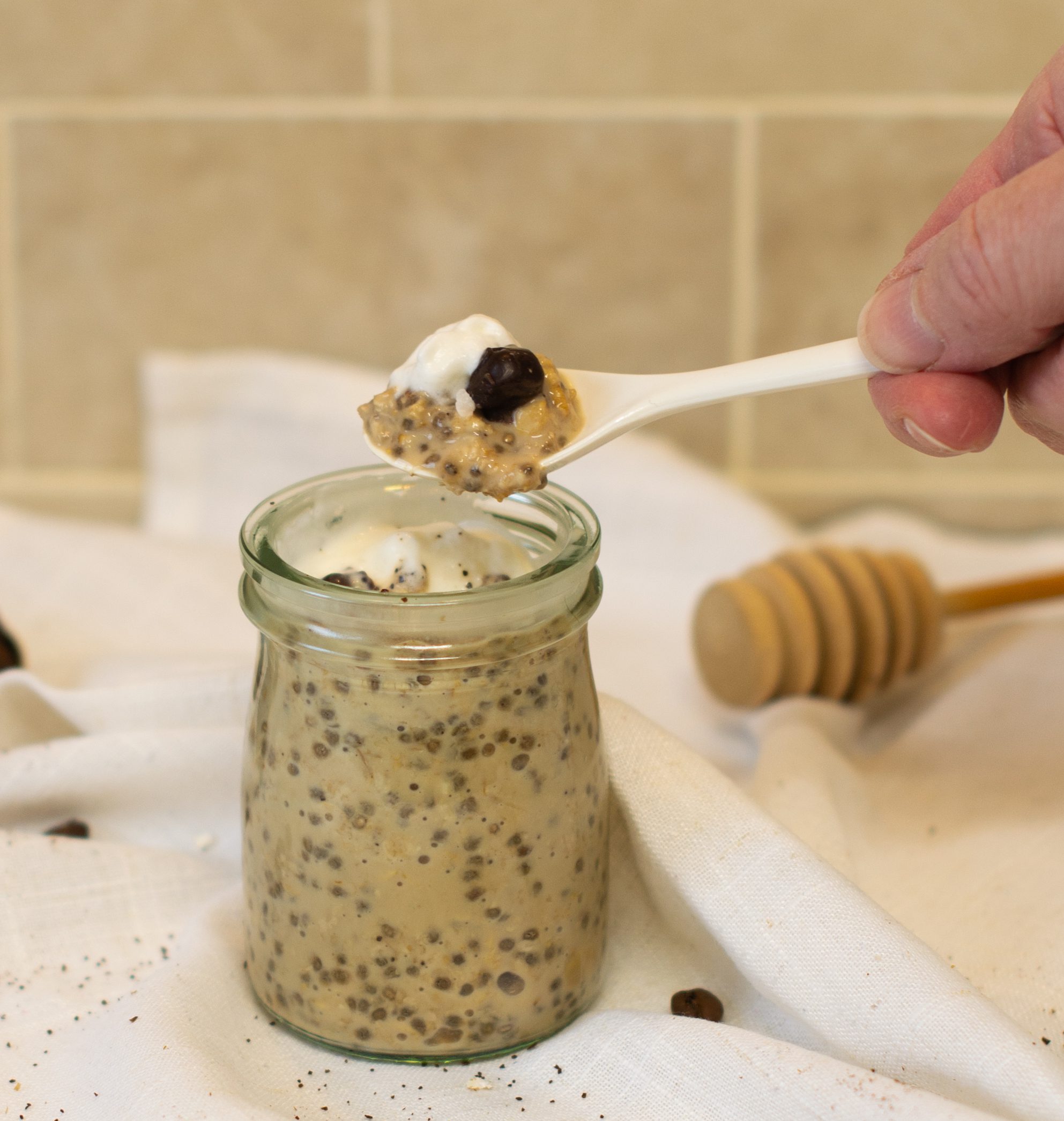 Taking a spoonful of coffee overnight oats with a white plastic teaspoon