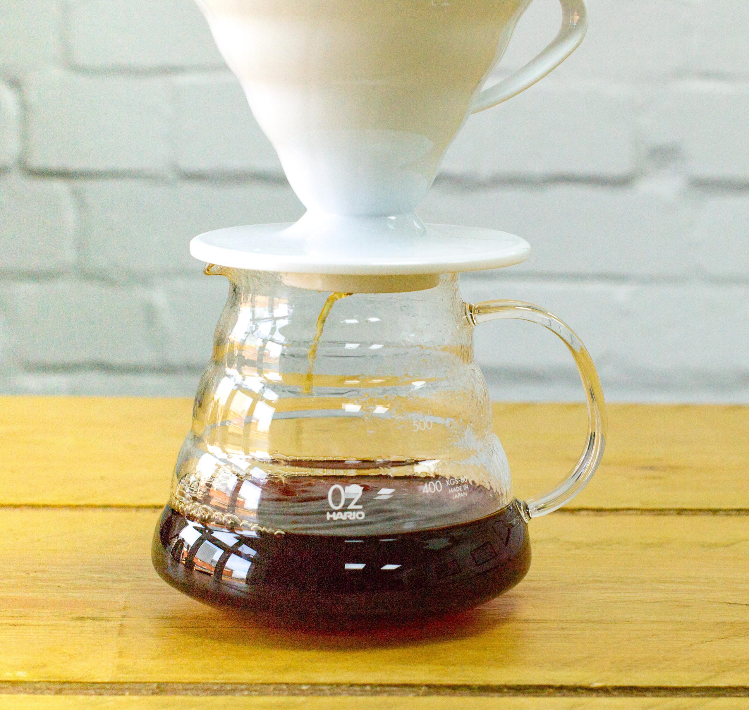 Coffee dripping from pour over device into clear jug