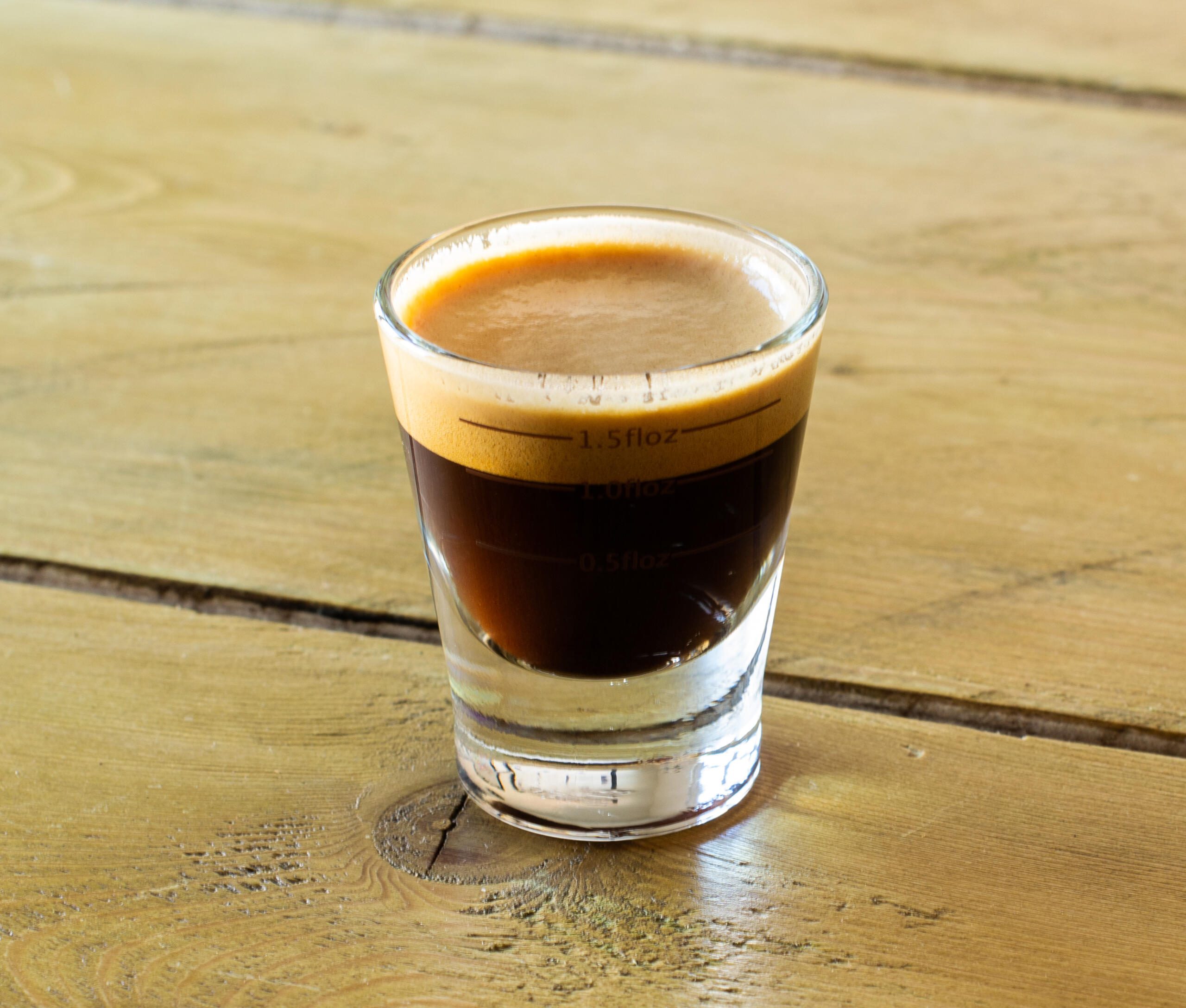 Ideal crema in an espresso glass on a wooden table 