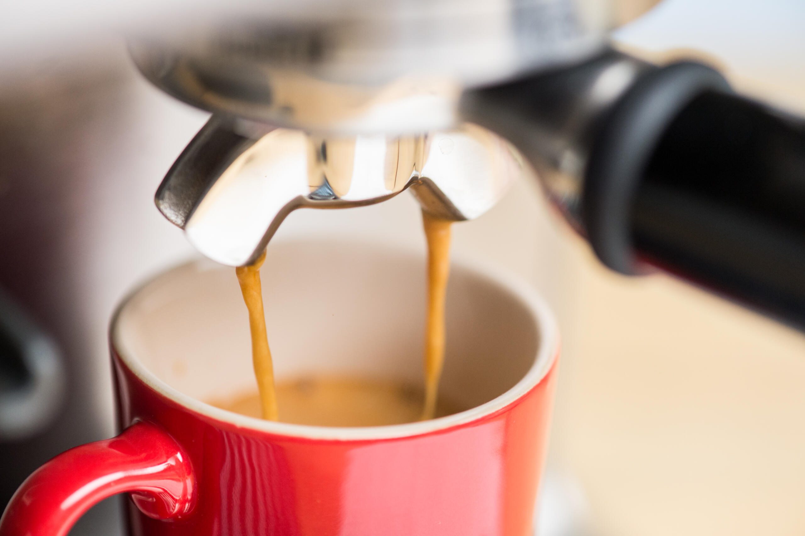 Espresso shot pouring into a red mug