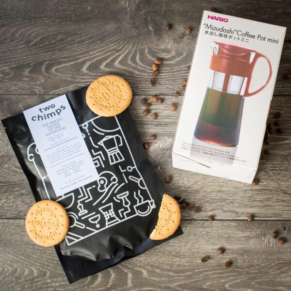 birdseye view of hario mizudashi red cold brew pot with a bag of two chimps coffee with coffee beans and biscuits for decoration