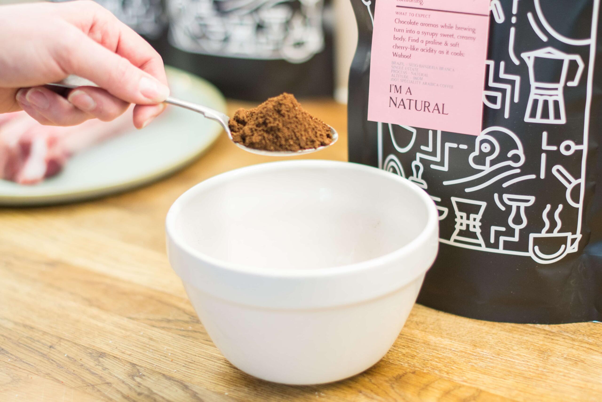 adding a tablespoon of ground two chimps coffee to a bowl