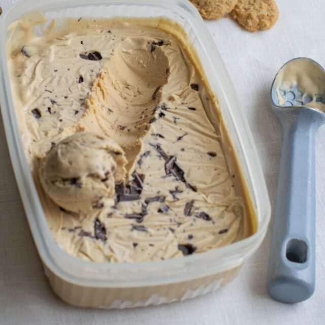 Tub of coffee ice cream with ice cream scoop