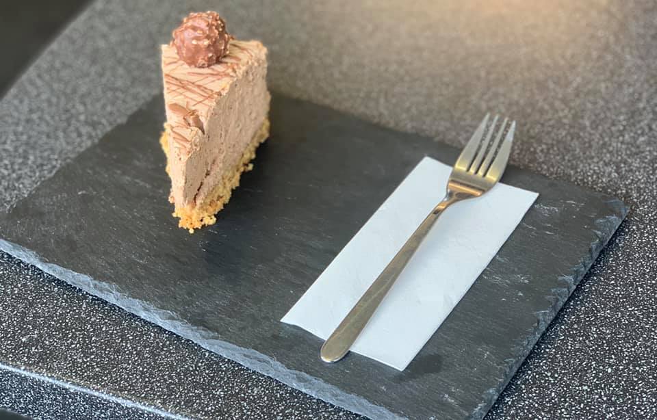 Ferrero Rocher cheesecake on a slate board with a napkin and fork