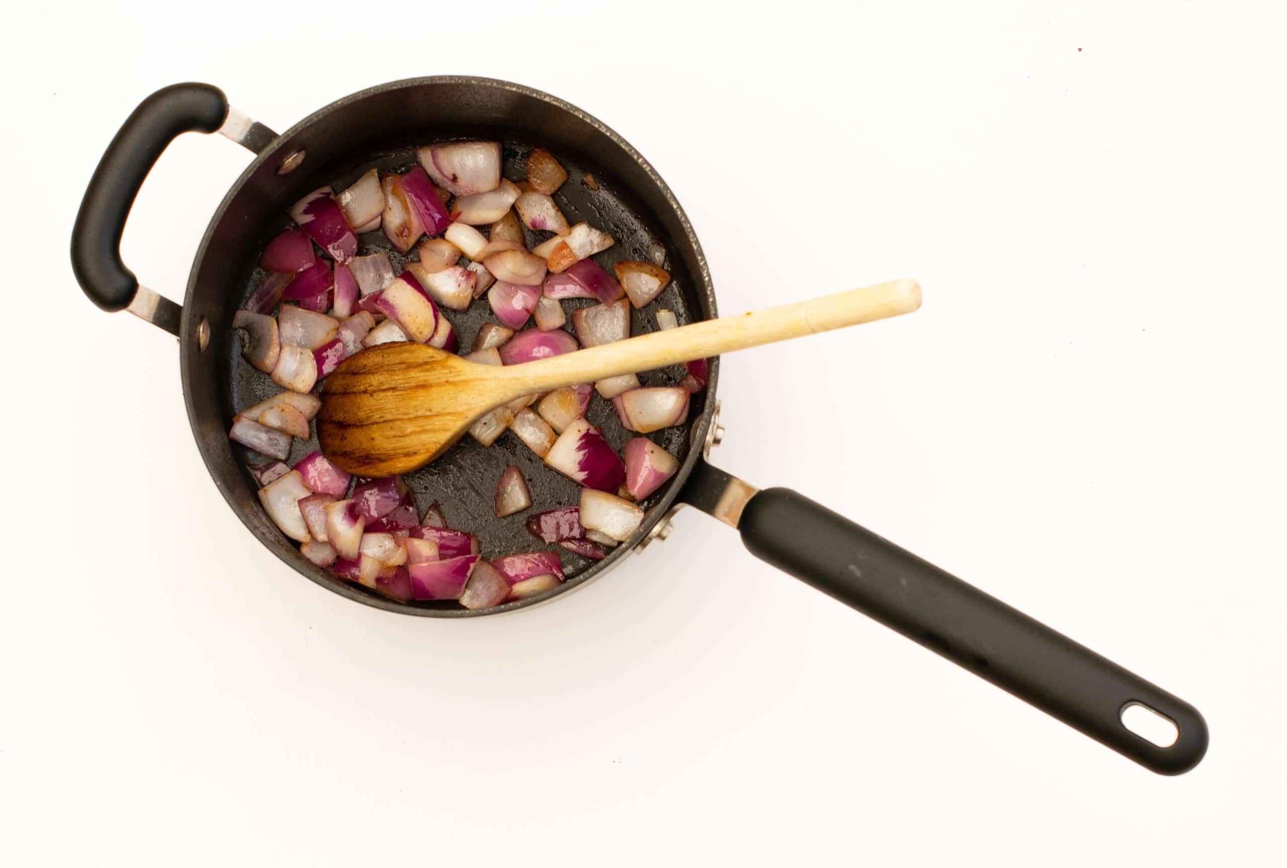 Frying onions in a black saucepan from above