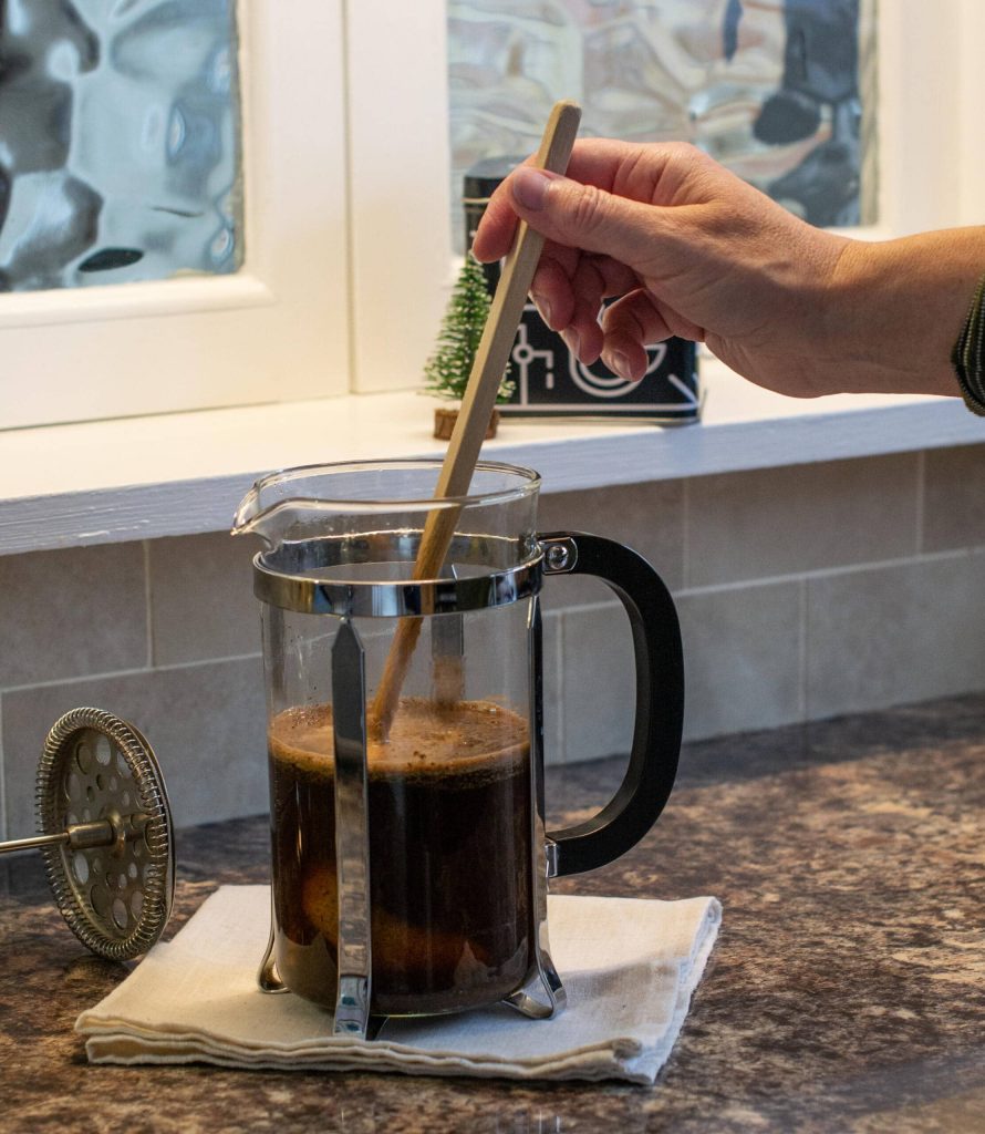 stirring a cafetiere to break the crust using a wooden spoon