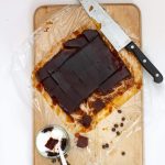 Overhead shot of brown jelly cubs on wooden board with glass coffee jelly dessert dish and knife