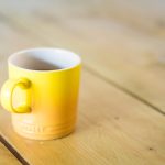 Yellow coffee mug sits on a wooden table