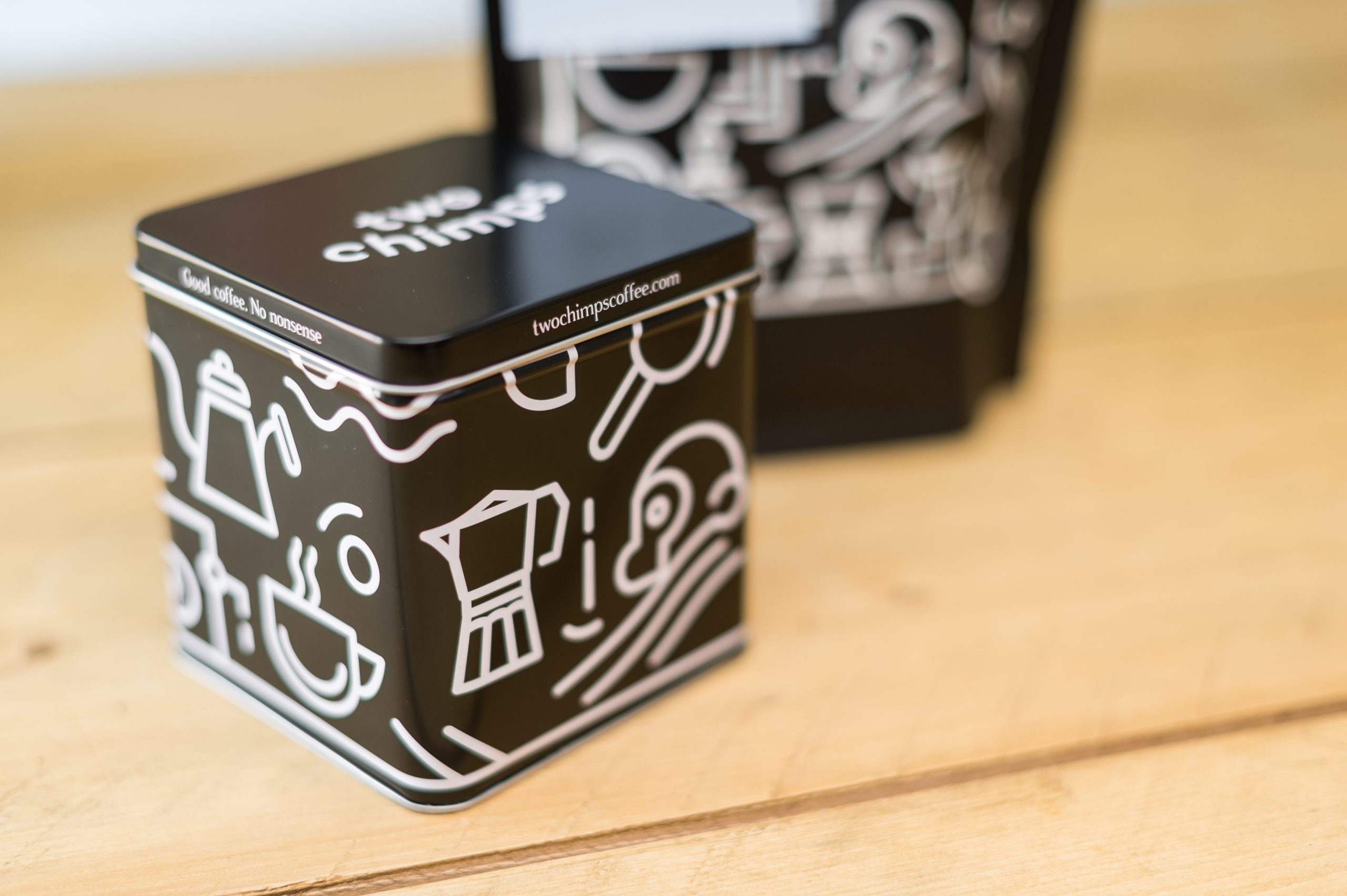 Two Chimps metal coffee tin and coffee pouch on a wooden table 