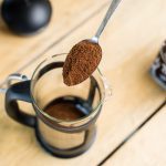 Spooning freshly ground coffee into a cafetiere jug