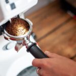 fresh coffee grounds tipping from a grinder into a portafilter